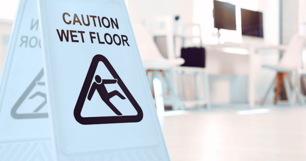 Caution wet floor sign in a bright office environment, emphasizing safety in cleaning practices for commercial spaces.